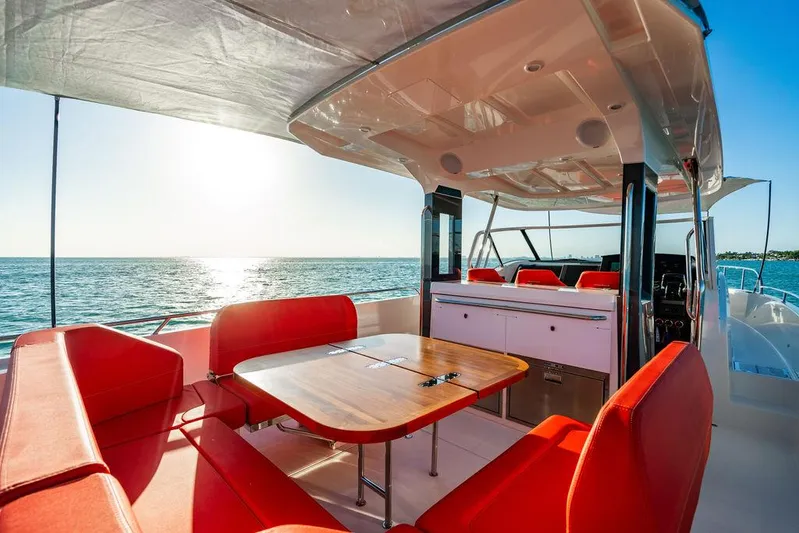 Volare Yacht Photos Pics Luxurious 2023 Nimbus T11 yacht interior with red seating, wooden table, and ocean view.