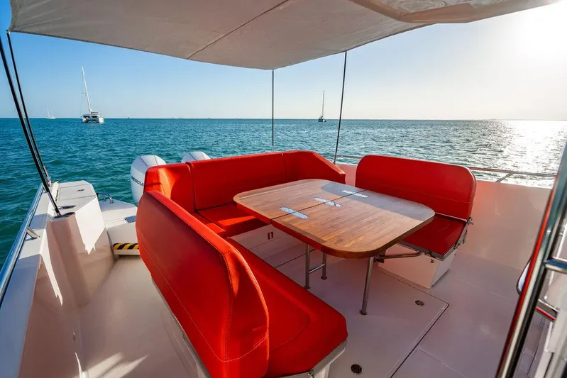 Volare Yacht Photos Pics 2023 Nimbus T11 boat with red seating and wooden table on deck, ocean view.