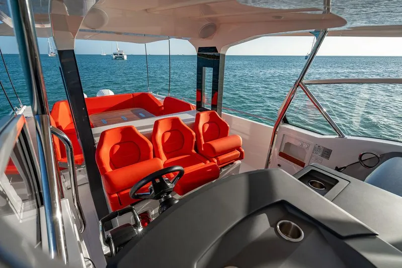 Volare Yacht Photos Pics 2023 Nimbus T11 boat interior with red seating, steering wheel, and ocean view.