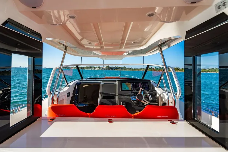 Volare Yacht Photos Pics 2023 Nimbus T11 boat interior with red seating and modern dashboard, overlooking blue water.
