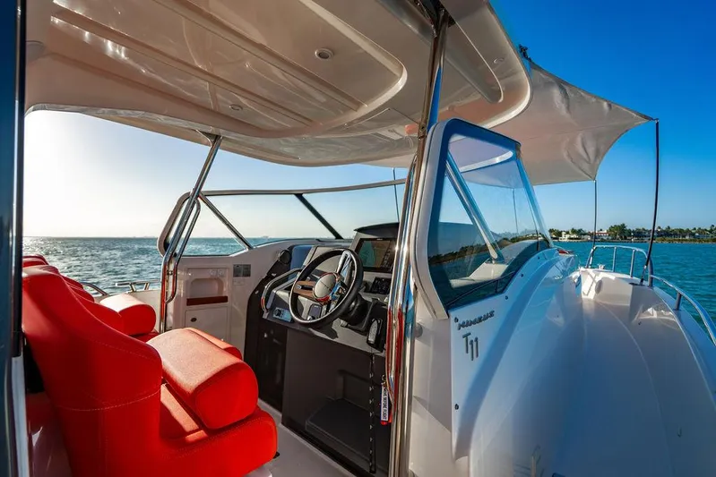 Volare Yacht Photos Pics 2023 Nimbus T11 boat interior with red seating, steering wheel, and ocean view.