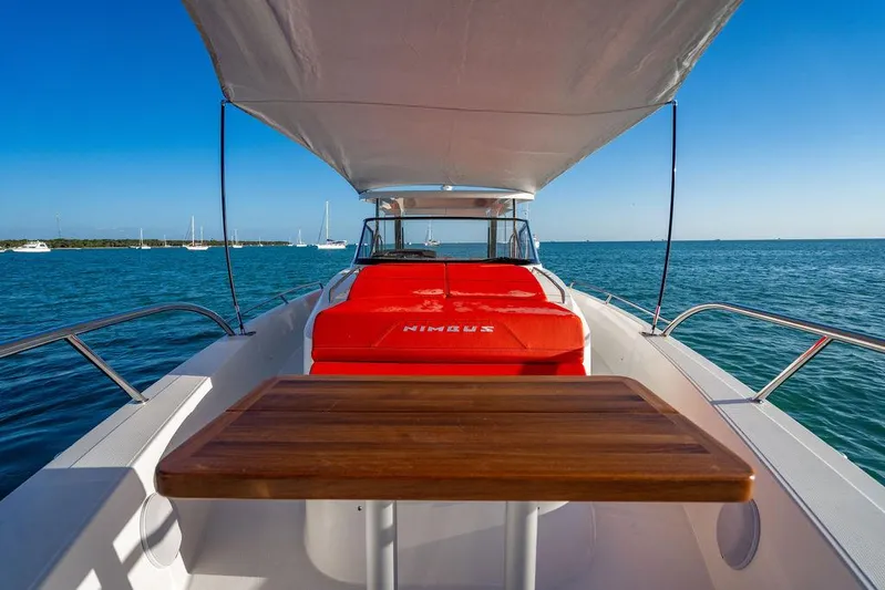 Volare Yacht Photos Pics Nimbus T11 2023 boat with canopy, wooden table, and red seating on open water.