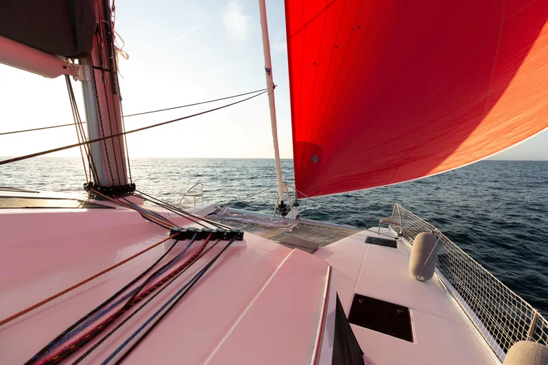 Aria Yacht Photos Pics 2023 Fountaine Pajot Elba 45 Catamaran sailing with vibrant red sail on open sea.