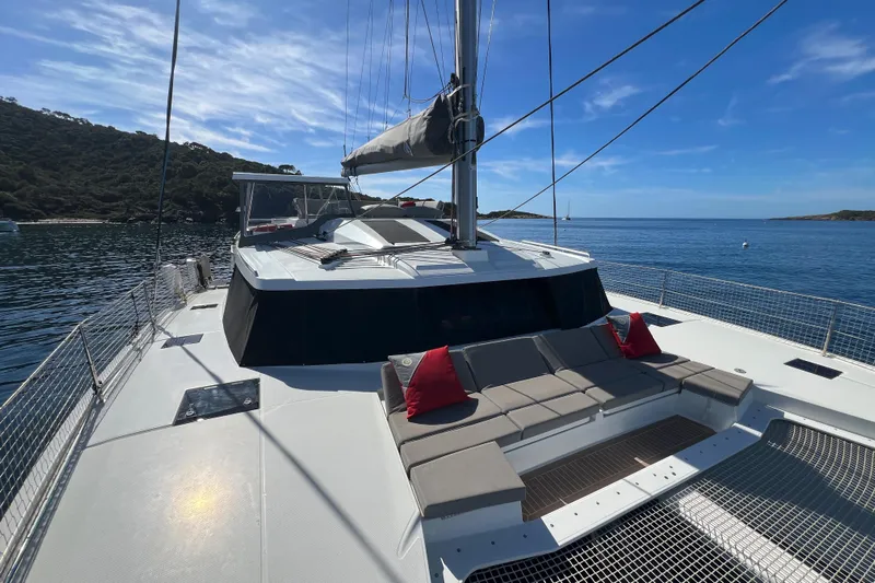 Aria Yacht Photos Pics 2023 Fountaine Pajot Elba 45 Catamaran on serene water with scenic backdrop.