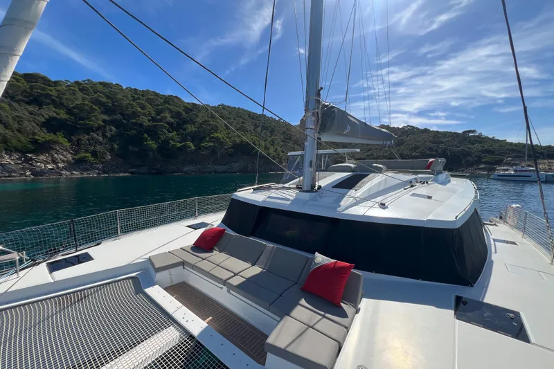 Aria Yacht Photos Pics 2023 Fountaine Pajot Elba 45 Catamaran anchored in scenic bay with lush greenery.