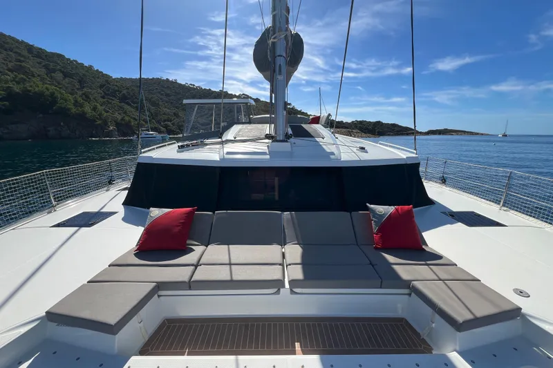 Aria Yacht Photos Pics 2023 Fountaine Pajot Elba 45 Catamaran with sun deck, red cushions, and scenic ocean view.