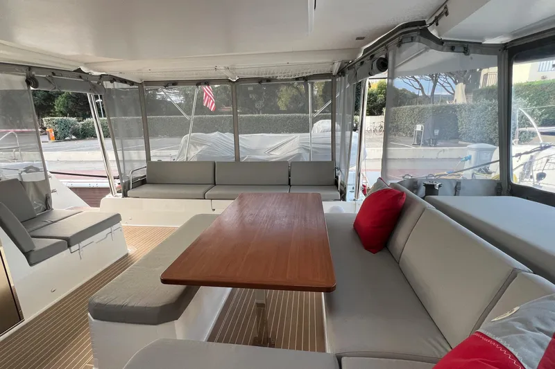 Aria Yacht Photos Pics 2023 Fountaine Pajot Elba 45 Catamaran interior with seating and wooden table.