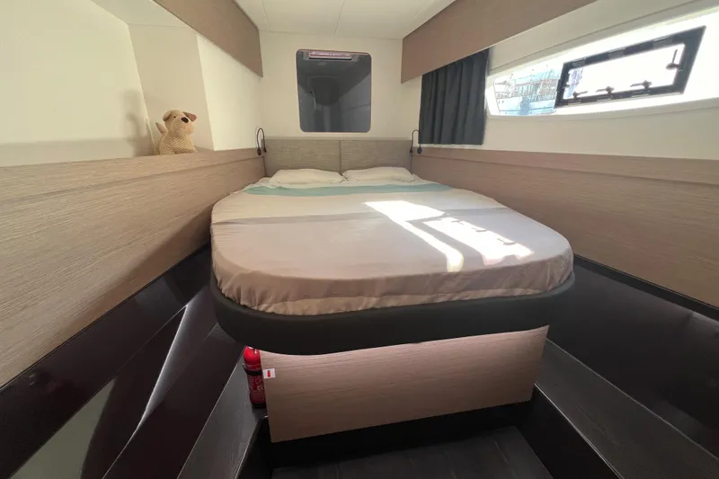 Aria Yacht Photos Pics 2023 Fountaine Pajot Elba 45 Catamaran cabin with bed, window, and plush toy.