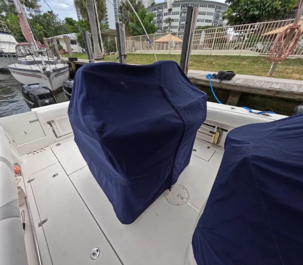  Yacht Photos Pics 2013 Boston Whaler 320 Outrage boat with covered seats docked near a marina.