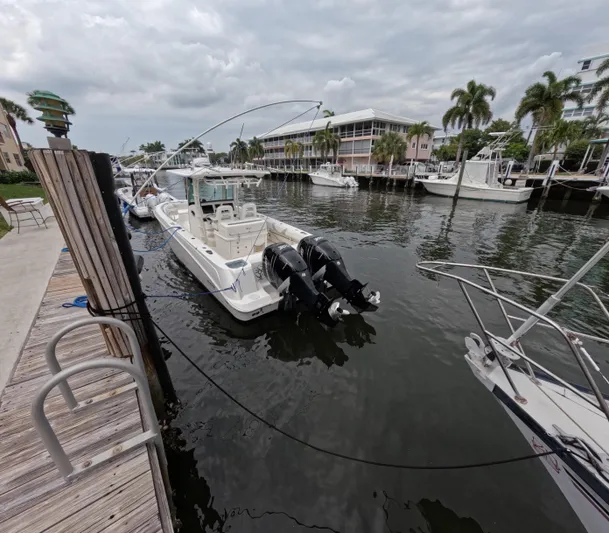  Yacht Photos Pics 2013 Boston Whaler 320 Outrage docked in a marina with palm trees and cloudy sky.