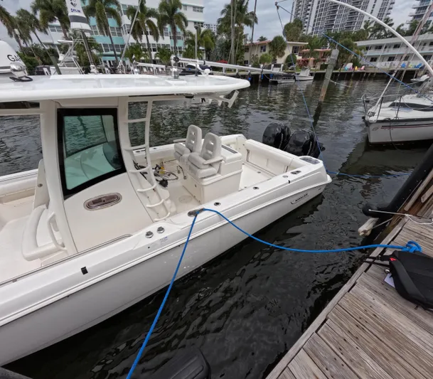  Yacht Photos Pics 2013 Boston Whaler 320 Outrage docked in a marina, surrounded by water and palm trees.