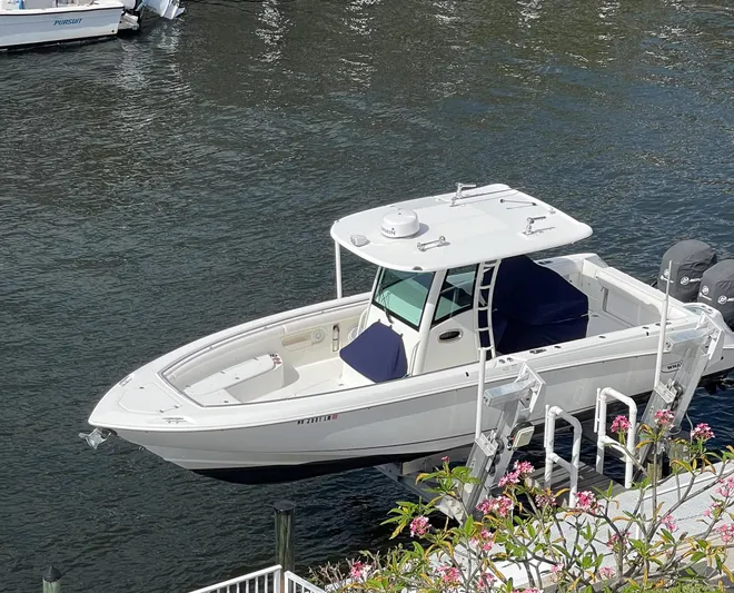  Yacht Photos Pics 2013 Boston Whaler 320 Outrage boat docked on calm water, surrounded by flowers.
