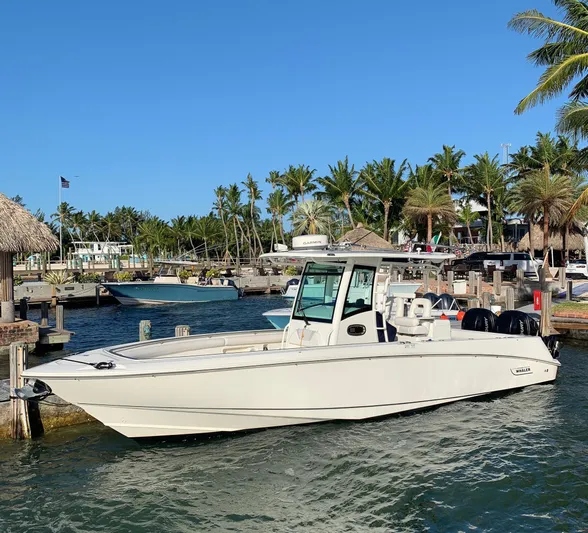  Yacht Photos Pics 2013 Boston Whaler 320 Outrage boat docked near palm trees and clear blue sky.