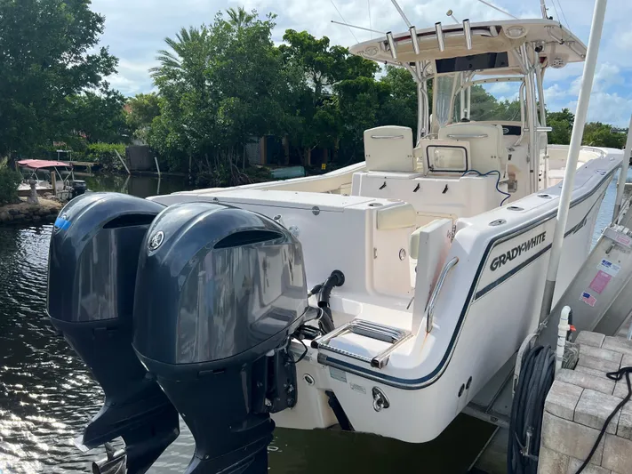  Yacht Photos Pics 2011 Grady-White Canyon 306 boat with dual outboard motors docked by lush greenery.