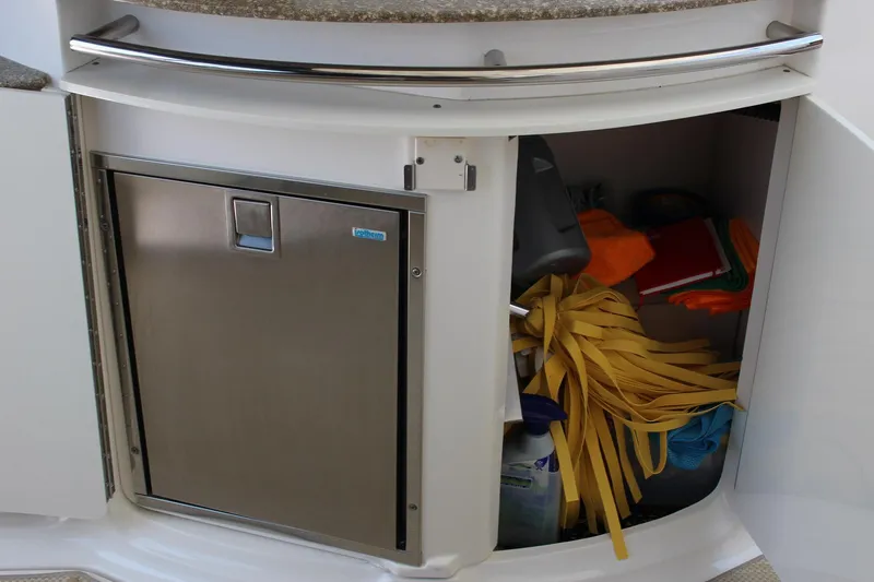 Happy Ours Yacht Photos Pics Storage compartment on a 2008 Chaparral 350 Signature Extended Plane boat, with various items inside.