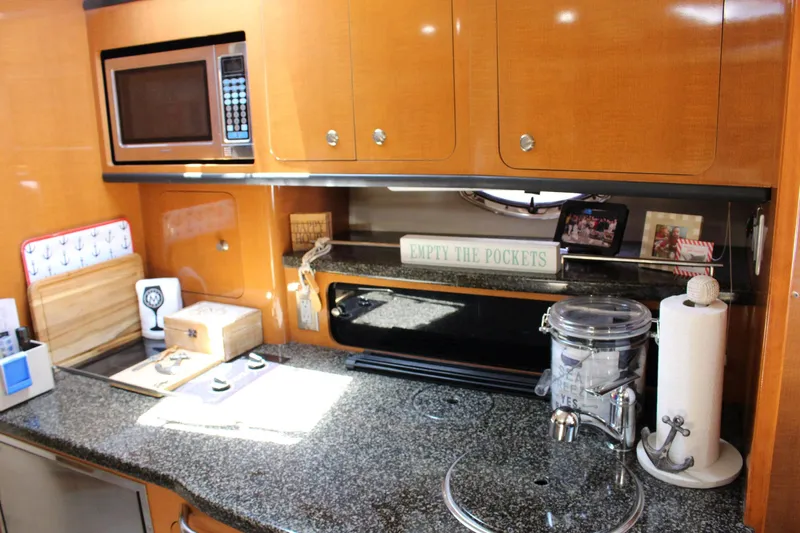 Happy Ours Yacht Photos Pics Kitchen area of 2008 Chaparral 350 Signature yacht with granite countertop and wooden cabinets.