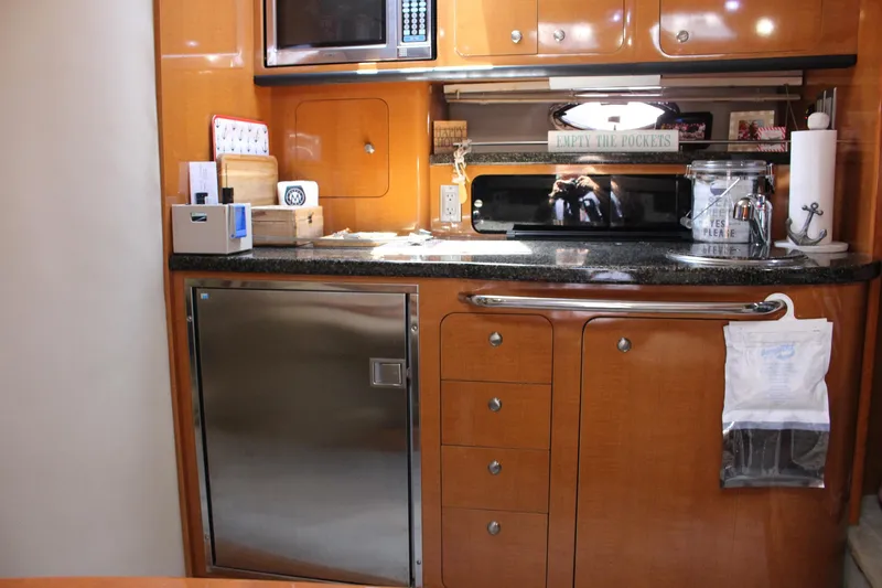Happy Ours Yacht Photos Pics Kitchen area of 2008 Chaparral 350 Signature Extended Plane with wooden cabinets and stainless steel appliances.