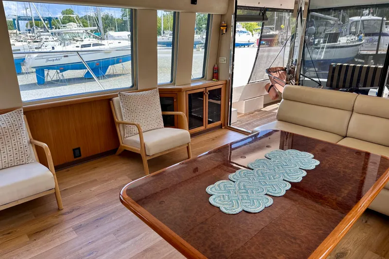 Chasing Sunsets Yacht Photos Pics Luxurious interior of 2000 Pacific Mariner 65 Motoryacht with elegant seating and wooden table.