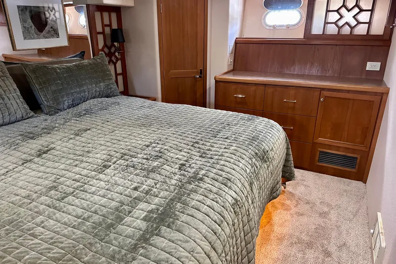 Chasing Sunsets Yacht Photos Pics Luxurious bedroom interior of 2000 Pacific Mariner 65 Motoryacht with plush bedding and wooden cabinetry.