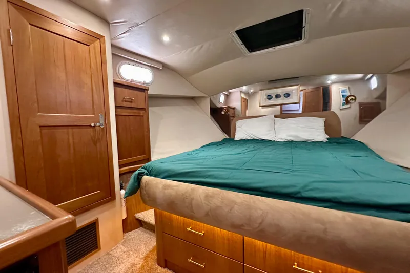 Chasing Sunsets Yacht Photos Pics Luxurious bedroom interior of 2000 Pacific Mariner 65 Motoryacht with cozy bedding and wooden cabinetry.