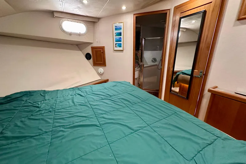 Chasing Sunsets Yacht Photos Pics Bedroom interior of 2000 Pacific Mariner 65 Motoryacht with green bedding and wooden accents.