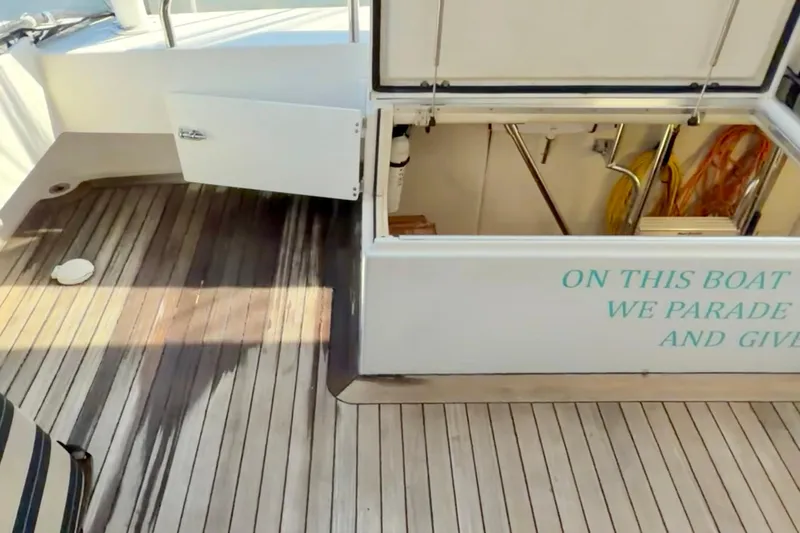 Chasing Sunsets Yacht Photos Pics 2000 Pacific Mariner 65 Motoryacht deck with open storage compartment and humorous text.