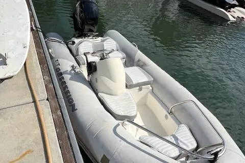 Obsession Yacht Photos Pics Inflatable boat docked beside a pier, featuring cushioned seating and an outboard motor.