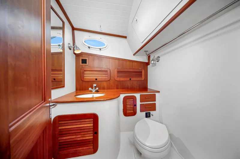 Midnight Yacht Photos Pics 2014 Hinckley Picnic Boat 37 MKIII bathroom with wooden cabinetry and porthole window.