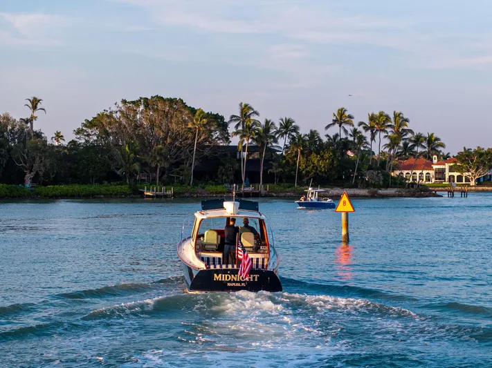 Midnight Yacht Photos Pics Hinckley Picnic Boat 37 MKIII cruising near palm-lined shore, 2014 model.
