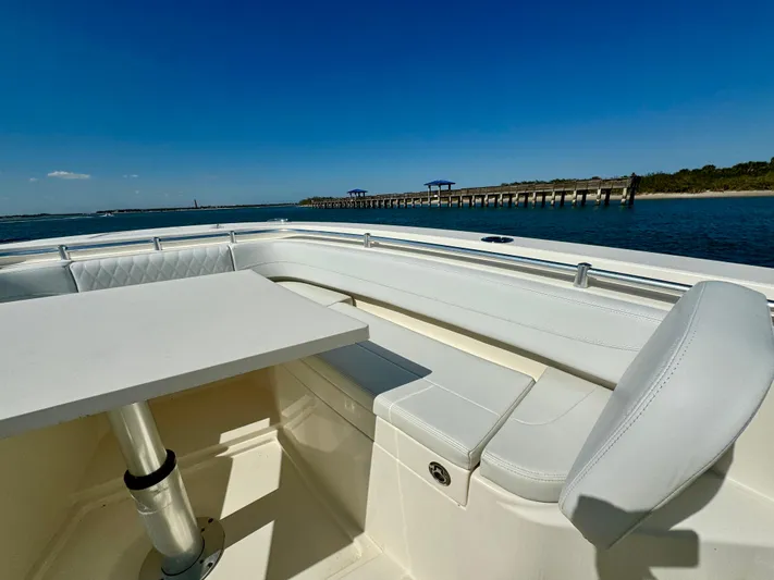  Yacht Photos Pics 2020 Cobia 350 Center Console boat interior with seating and table, near a scenic pier.