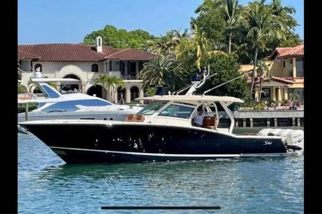  Yacht Photos Pics 2019 Scout 420 LXF boat cruising near waterfront homes with palm trees.