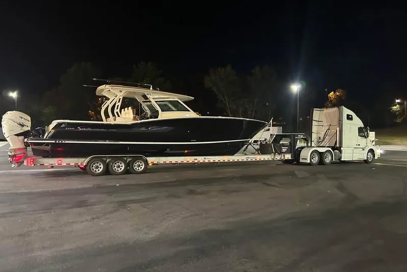  Yacht Photos Pics 2019 Scout 420 LXF boat on trailer, transported by a truck at night.