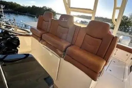  Yacht Photos Pics 2019 Scout 420 LXF boat with brown leather seating, docked by a scenic waterfront.