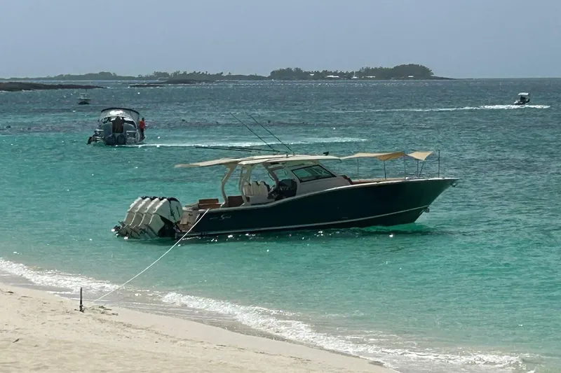  Yacht Photos Pics 2019 Scout 420 LXF boat anchored in turquoise waters near a sandy beach.