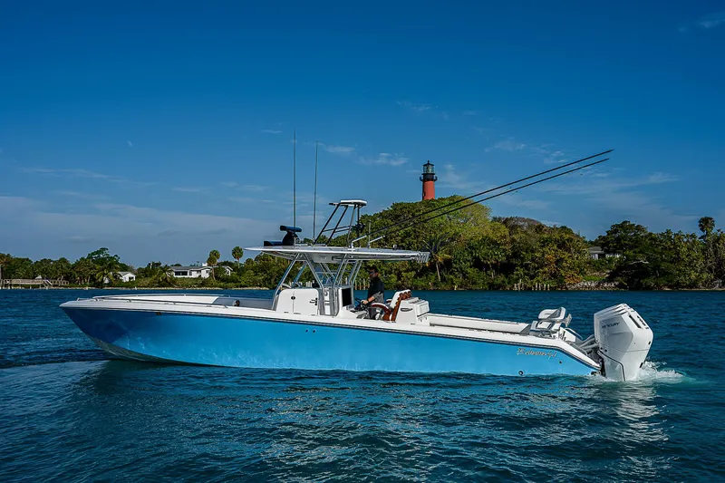 T/t Waterfront Yacht Photos Pics 2013 Bahama Quad V10's boat cruising near a lighthouse on a sunny day.