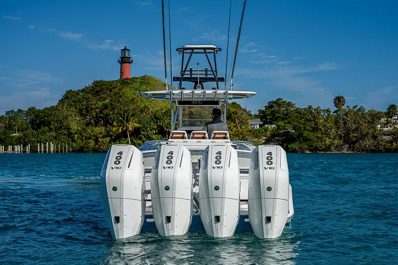 T/t Waterfront Yacht Photos Pics Bahama Quad V10's 2013 boat with four engines, cruising near a lighthouse.