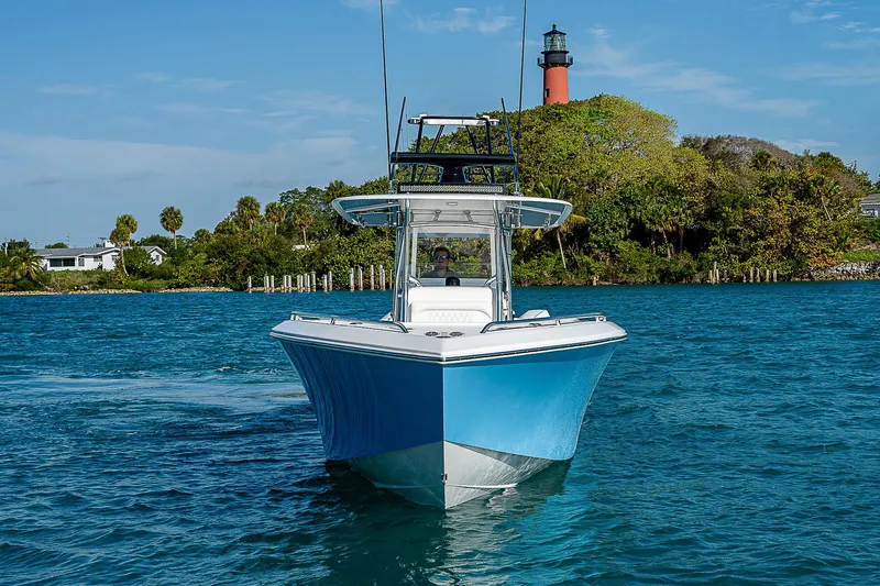 T/t Waterfront Yacht Photos Pics 2013 Bahama Quad V10's boat cruising near a lighthouse on a sunny day.