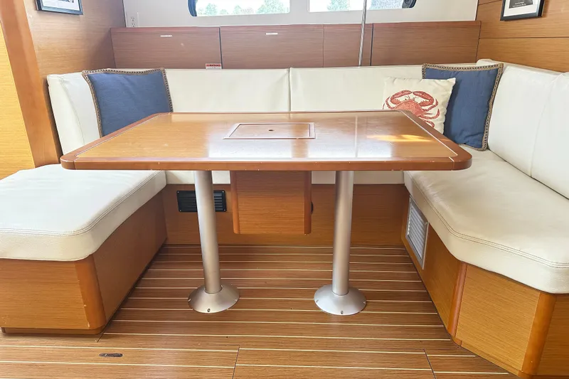 Northern Lights Yacht Photos Pics 2015 Jeanneau Sun Odyssey 469 interior with wooden table and white cushioned seating.