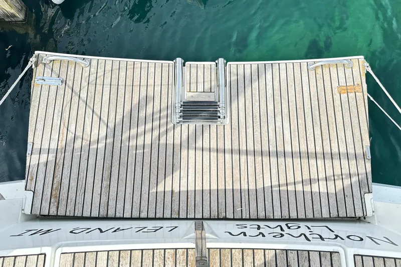 Northern Lights Yacht Photos Pics Jeanneau Sun Odyssey 469 (2015) yacht stern with wooden deck and ladder, docked in clear water.