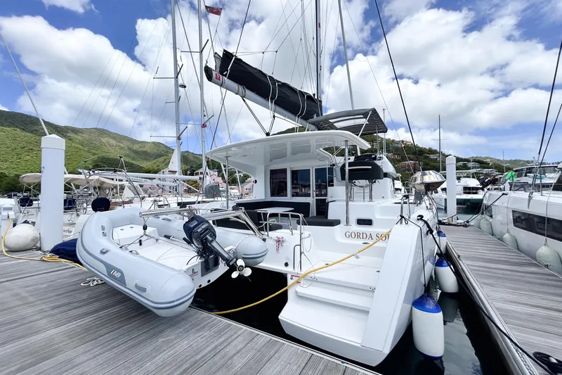 Oasis Yacht Photos Pics 2025 Lagoon 40 catamaran docked at marina, featuring inflatable dinghy and scenic background.