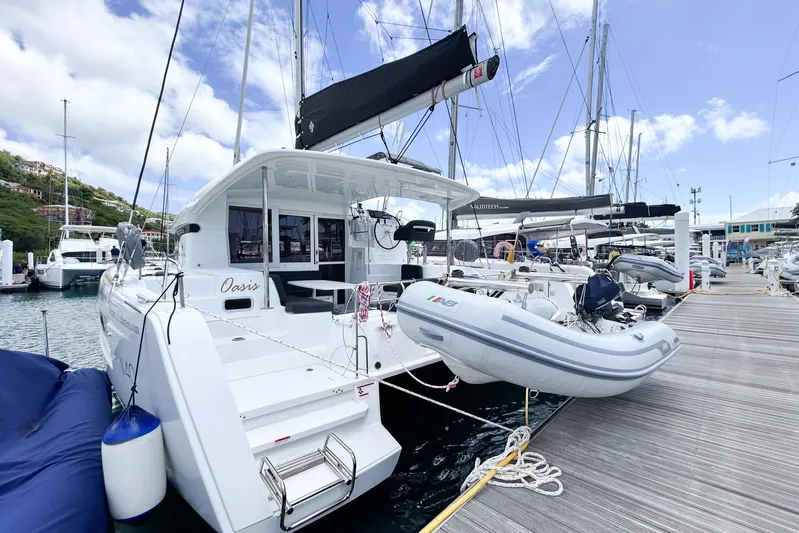 Oasis Yacht Photos Pics 2025 Lagoon 40 catamaran docked at marina with inflatable dinghy attached.