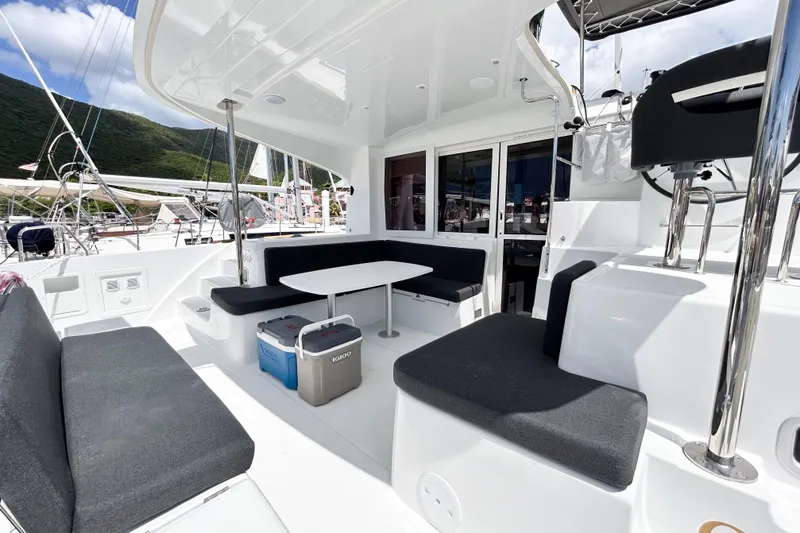 Oasis Yacht Photos Pics Spacious deck of 2025 Lagoon 40 catamaran with seating and table, docked at marina.