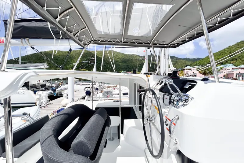 Oasis Yacht Photos Pics Modern 2025 Lagoon 40 catamaran cockpit with steering wheel, docked in scenic marina.