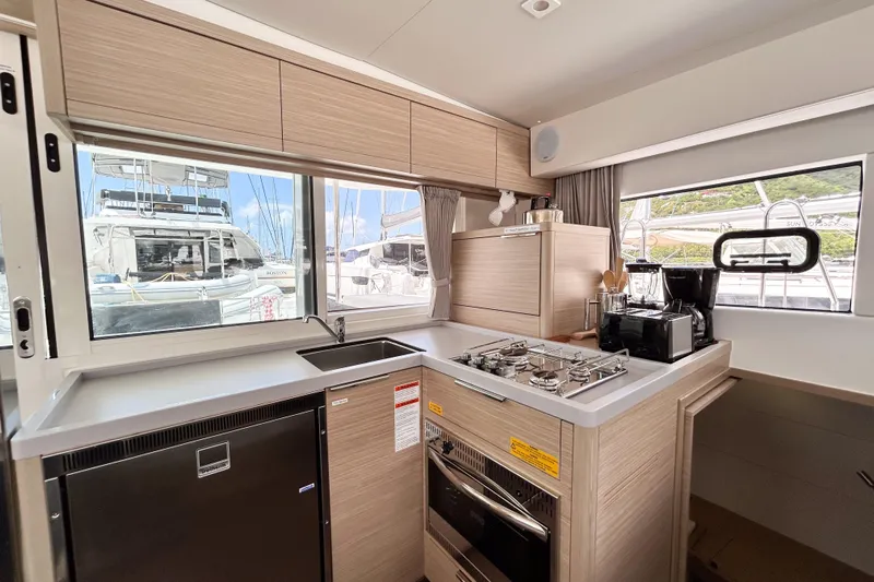Oasis Yacht Photos Pics Modern kitchen interior of 2025 Lagoon 40 catamaran with appliances and scenic marina view.