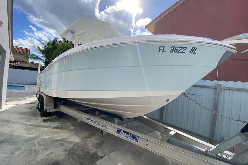  Yacht Photos Pics 2018 Robalo R242 Center Console boat on trailer, parked in driveway under sunny sky.