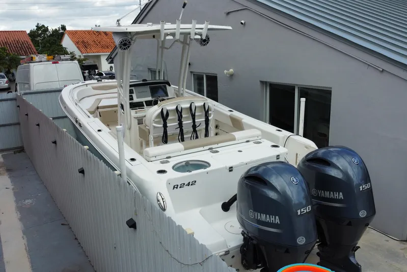  Yacht Photos Pics 2018 Robalo R242 Center Console boat with dual Yamaha 150 engines, parked beside a house.
