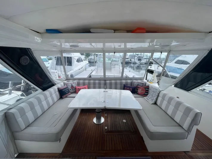 Ohana Yacht Photos Pics Interior of 2013 Sealine S450 yacht with striped seating and table, docked at marina.