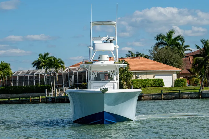 Rock N Reel Yacht Photos Pics 2018 Yellowfin 36 Offshore boat cruising near waterfront homes, under a clear blue sky.