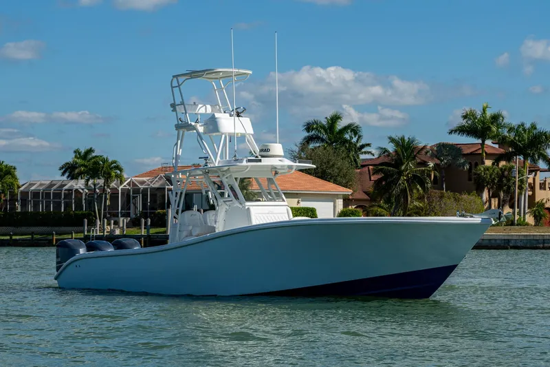 Rock N Reel Yacht Photos Pics 2018 Yellowfin 36 Offshore boat on water, with palm trees and houses in the background.
