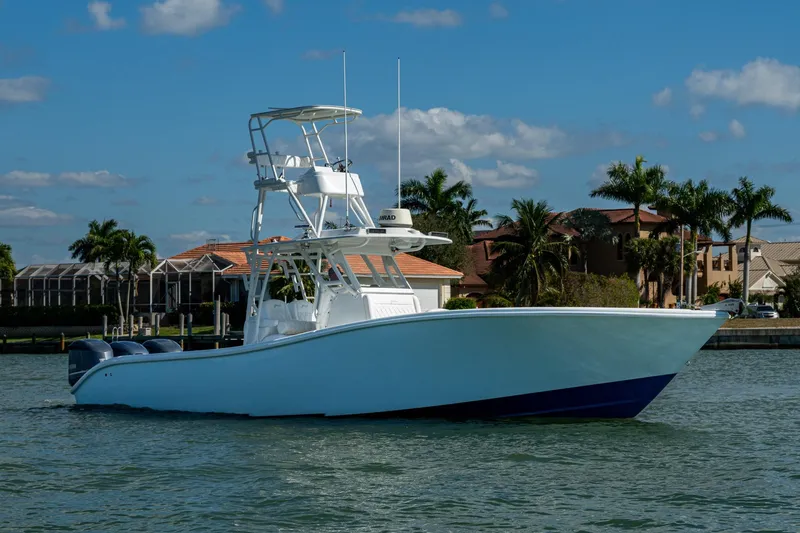 Rock N Reel Yacht Photos Pics 2018 Yellowfin 36 Offshore boat on water, with palm trees and houses in the background.